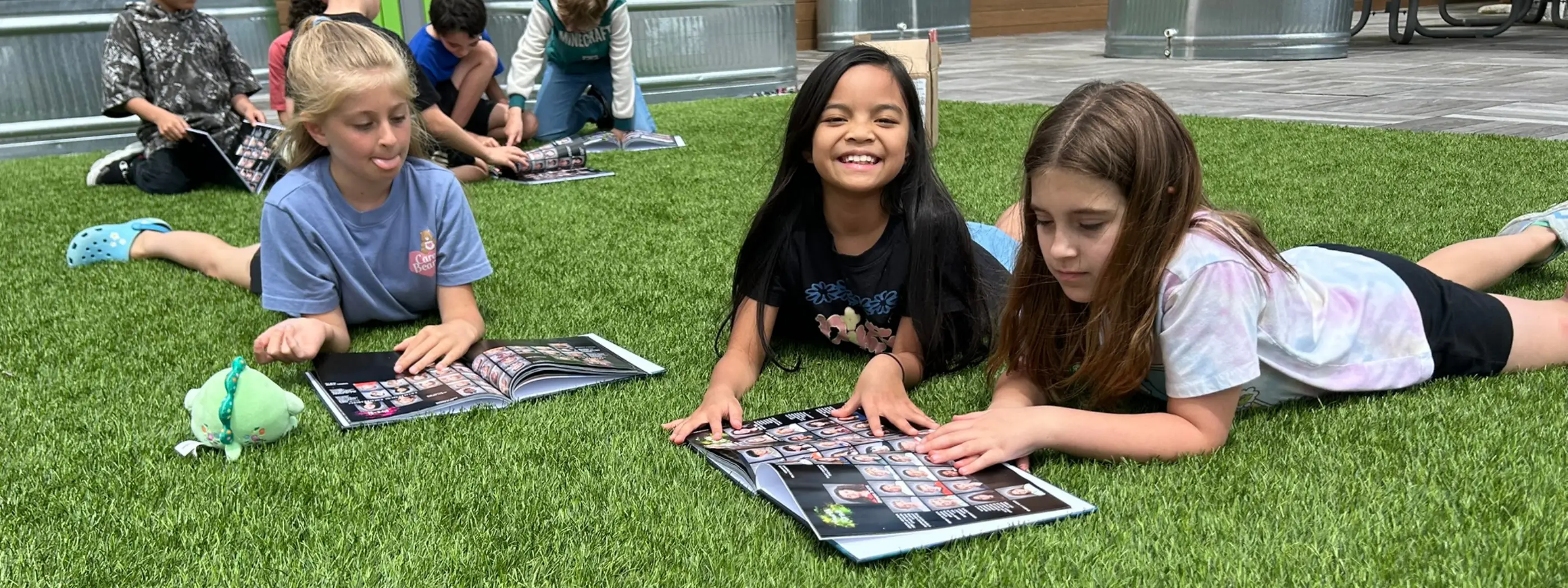 Students lying on the grass looking through their yearbooks